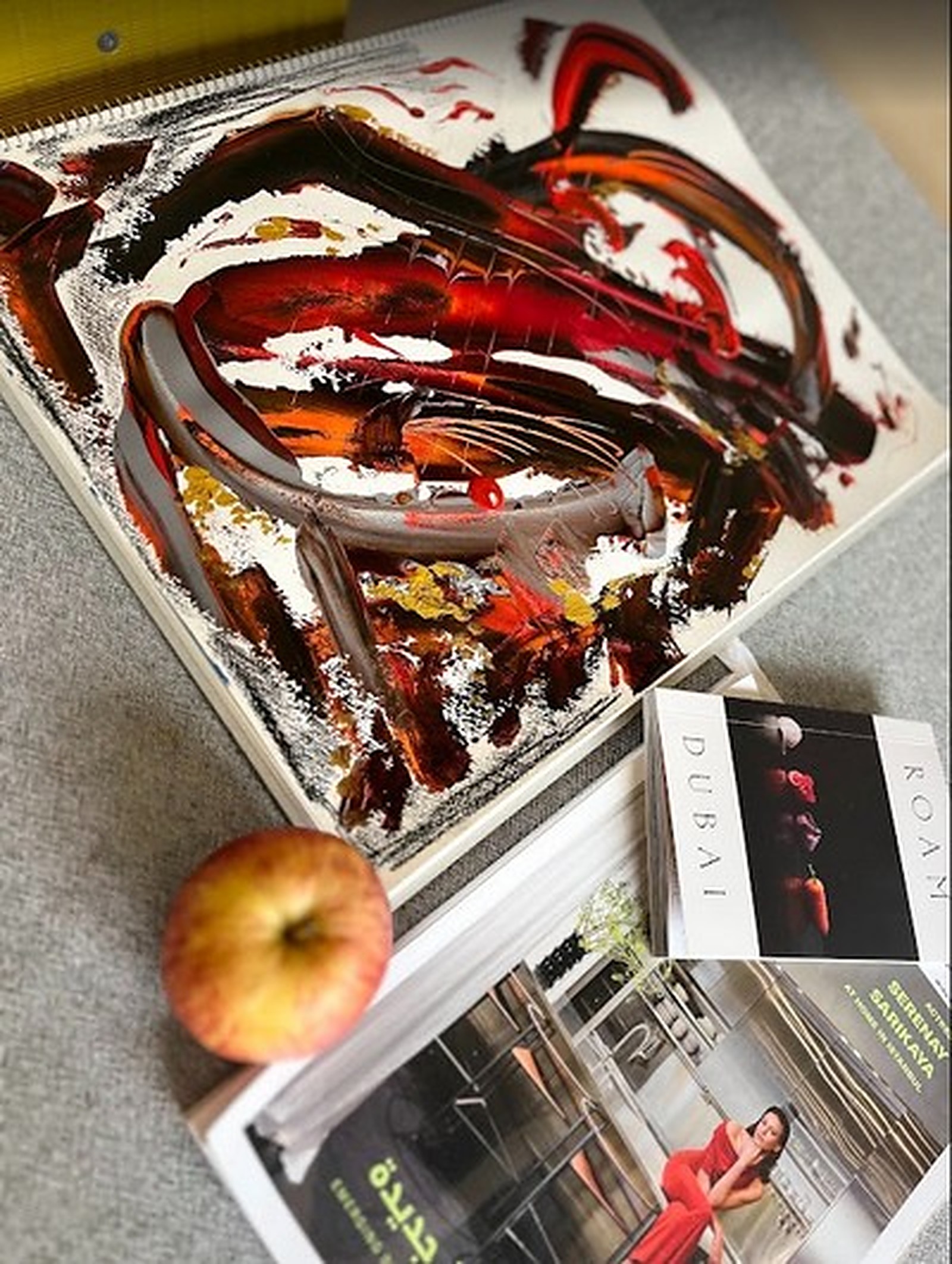 A vivid red painting with an apple and books